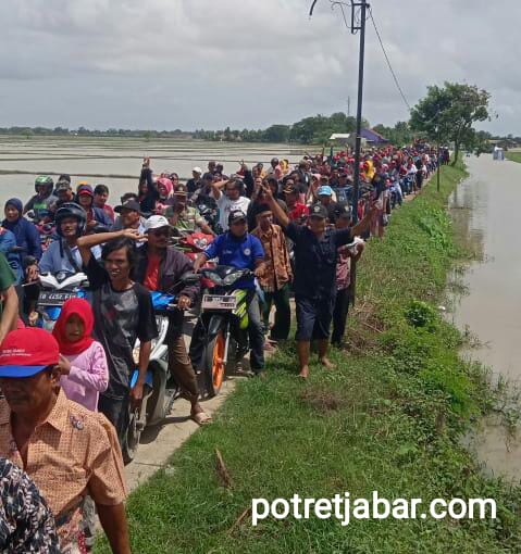 Antusias warga Desa Karya Makmur mengiringi kandidat Calon Kepala Desa meski dilanda banjir. 